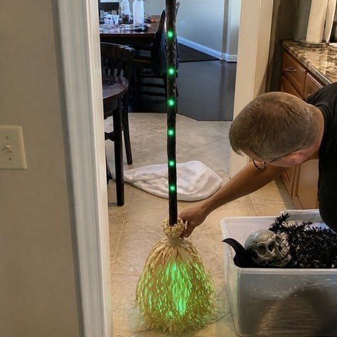 Setting up the animated broom beside Halloween decorations