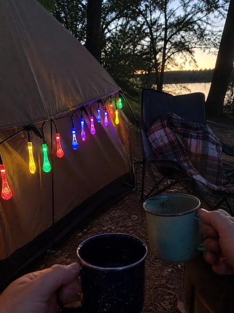 Multicolor teardrop lights hanging from a camping tent at dusk