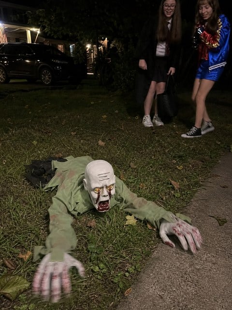 Crawling zombie decoration surprising trick-or-treaters on a lawn