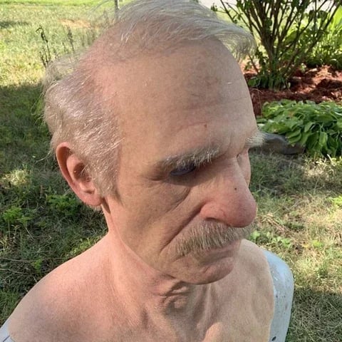 Elderly-character mask photographed outdoors from the side