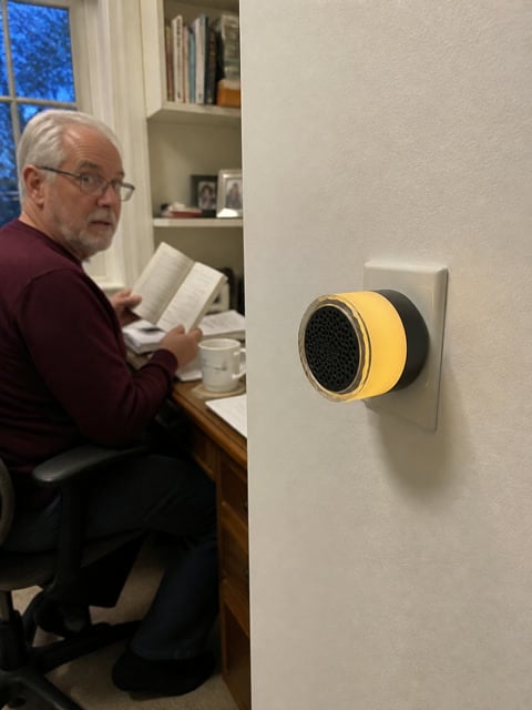 A black plug-in doorbell chime glowing near a home office