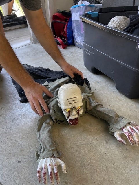 Crawling zombie decoration being unpacked in a garage