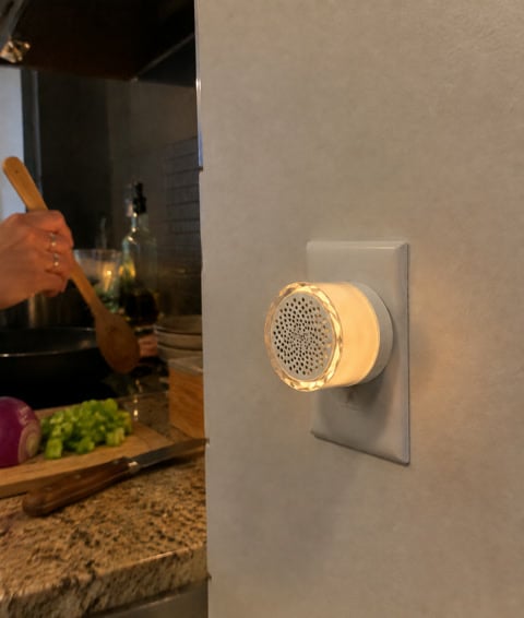 A white plug-in doorbell chime glowing in a lived-in kitchen