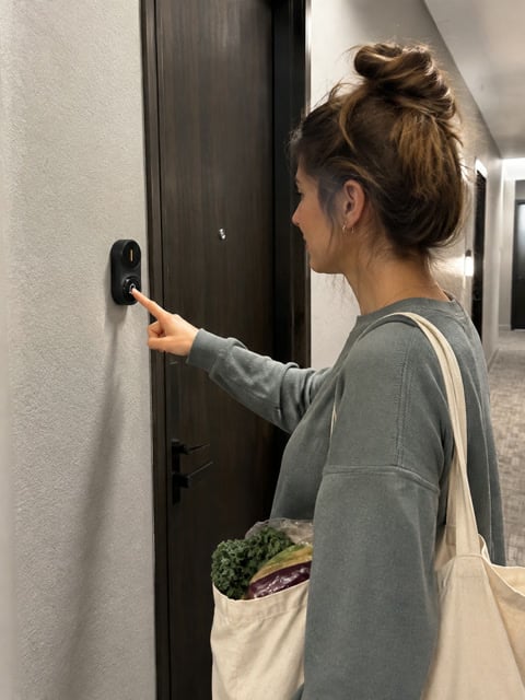 An apartment visitor pressing a black wireless doorbell button