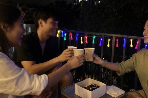 Friends enjoying a small balcony party with multicolor teardrop lights