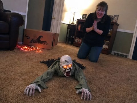 Family testing a crawling zombie decoration in a living room